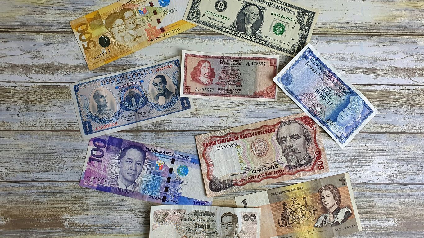 a bunch of different currency sitting on top of a wooden table