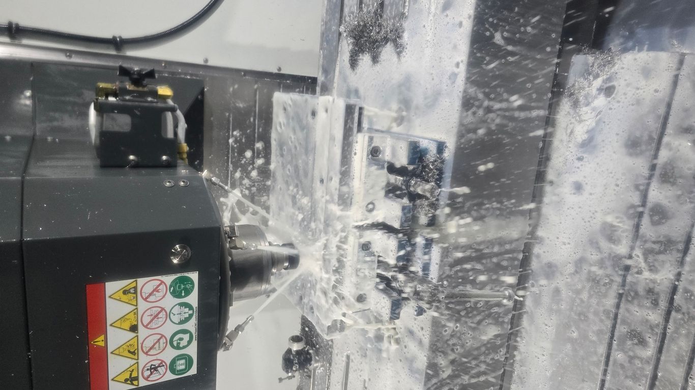 A CNC machine is cutting metal with coolant spraying.