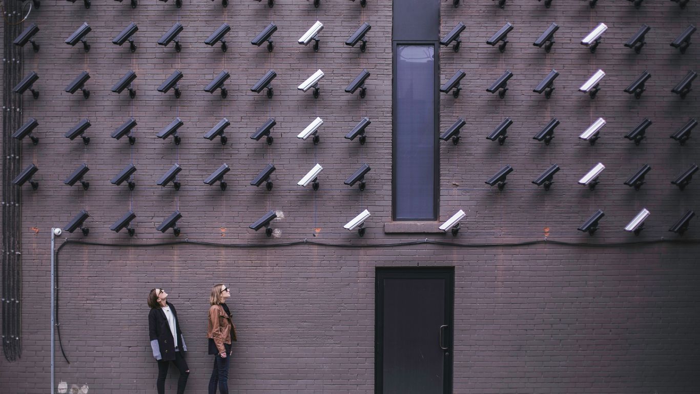 two women facing security camera above mounted on structure