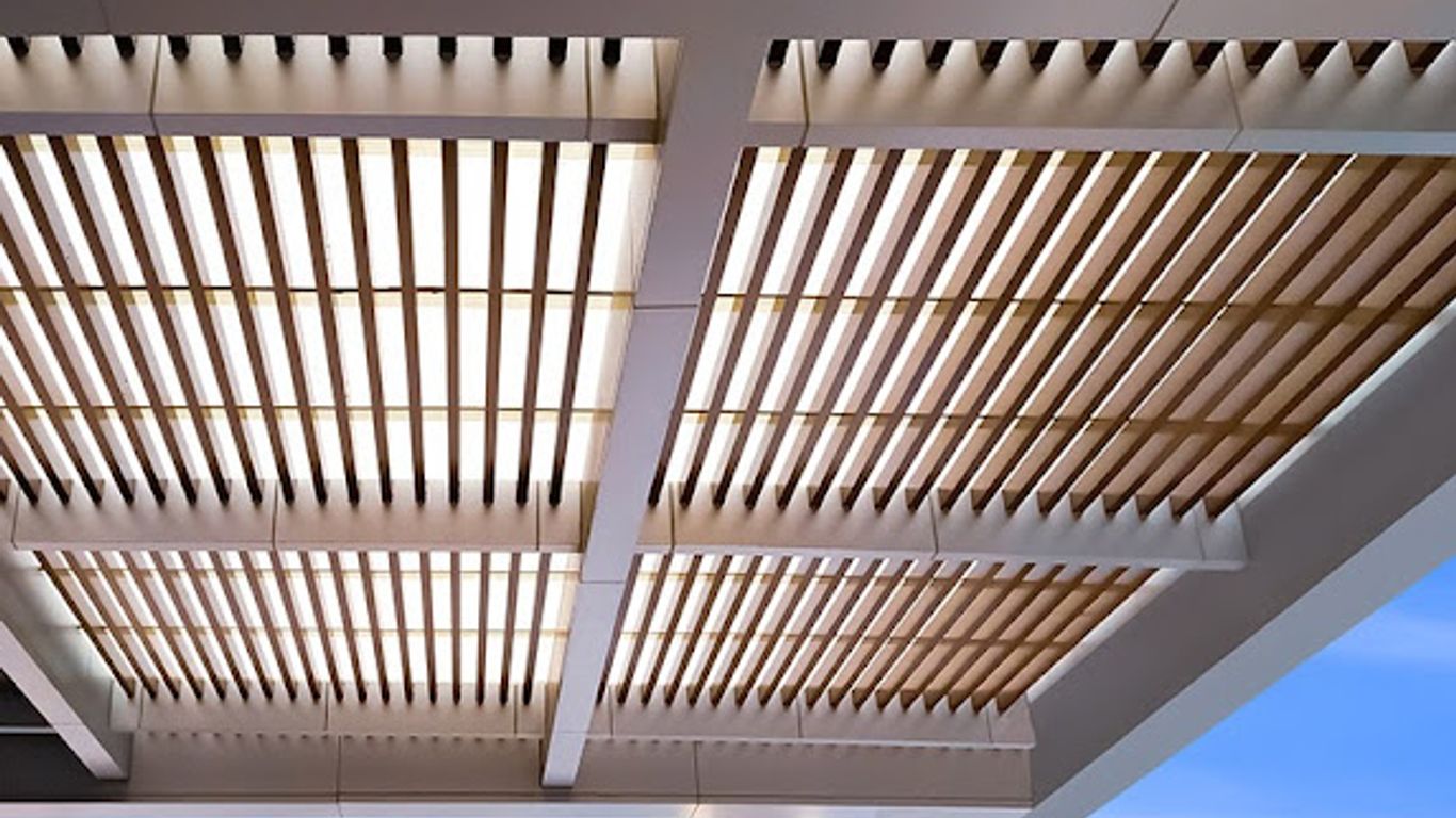 Modern architectural canopy with wooden slats against a bright blue sky.