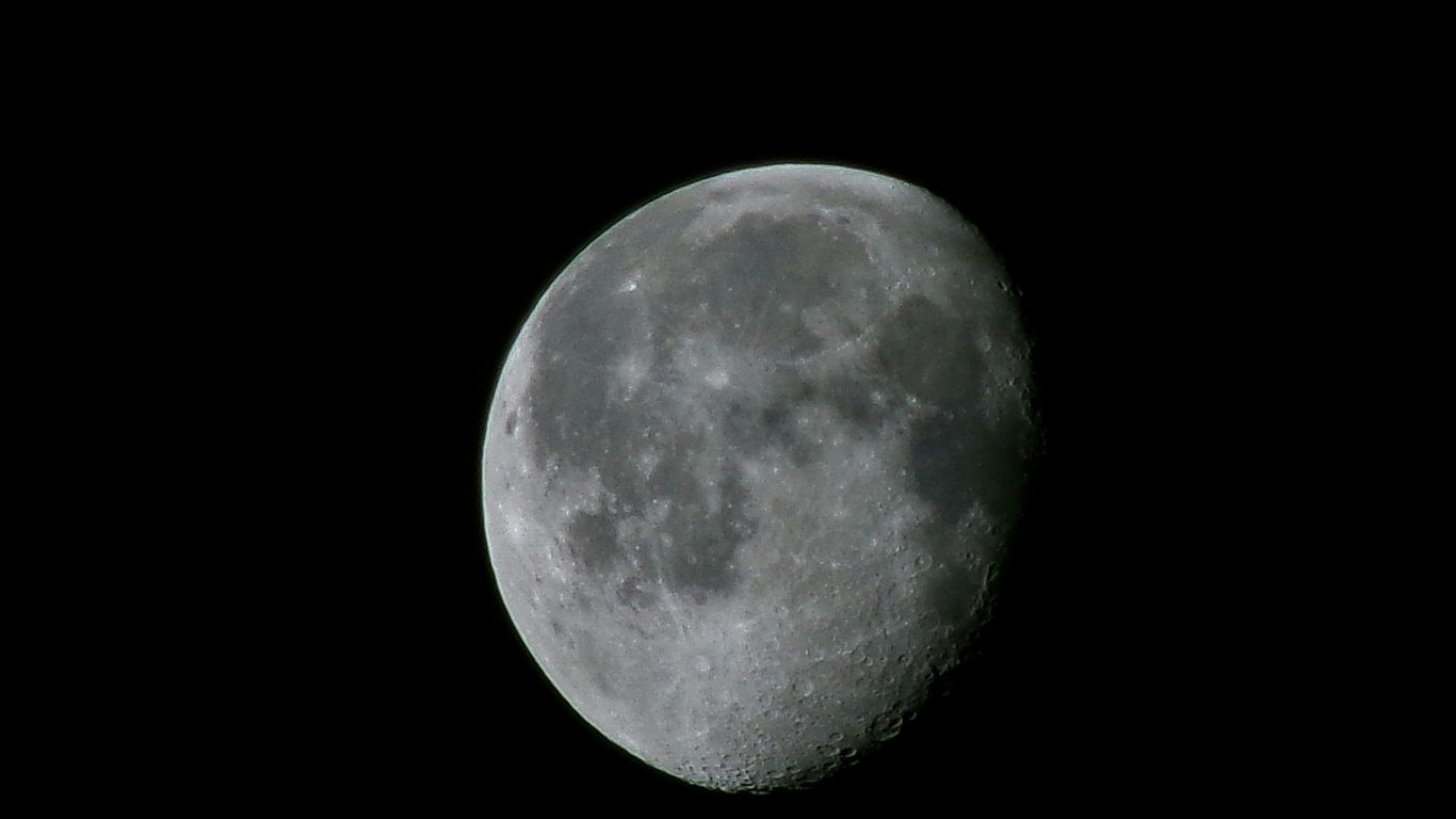 A waxing gibbous moon against a black sky.