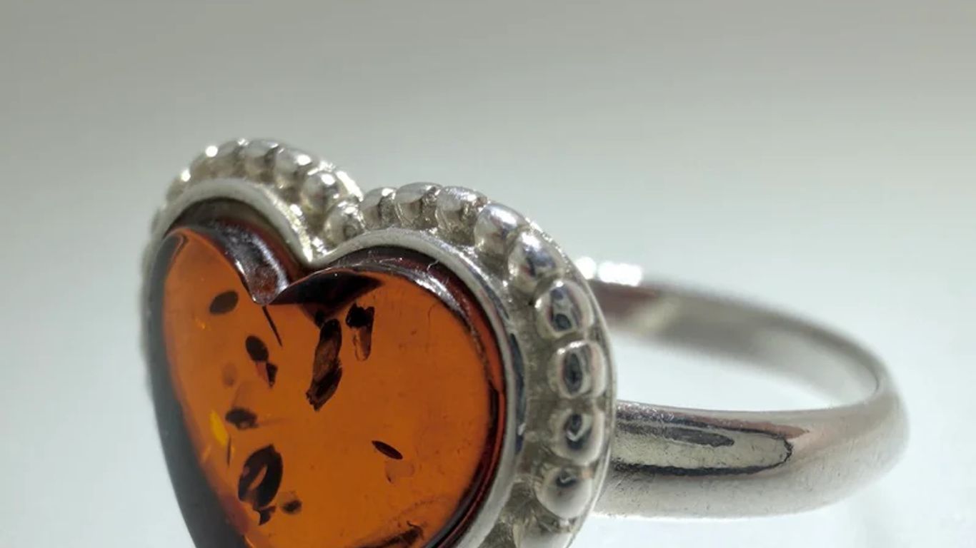 A silver ring with a heart-shaped amber stone.