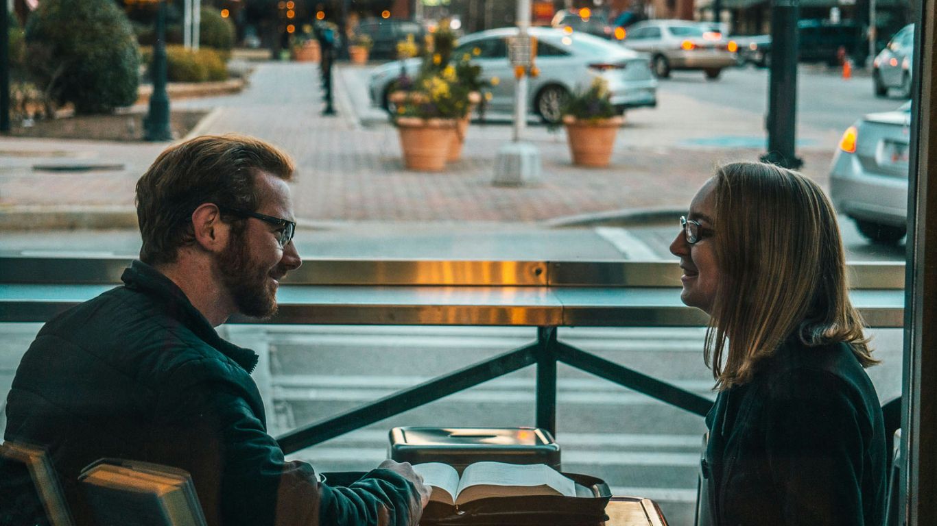 man and woman sitting while talking during daytime