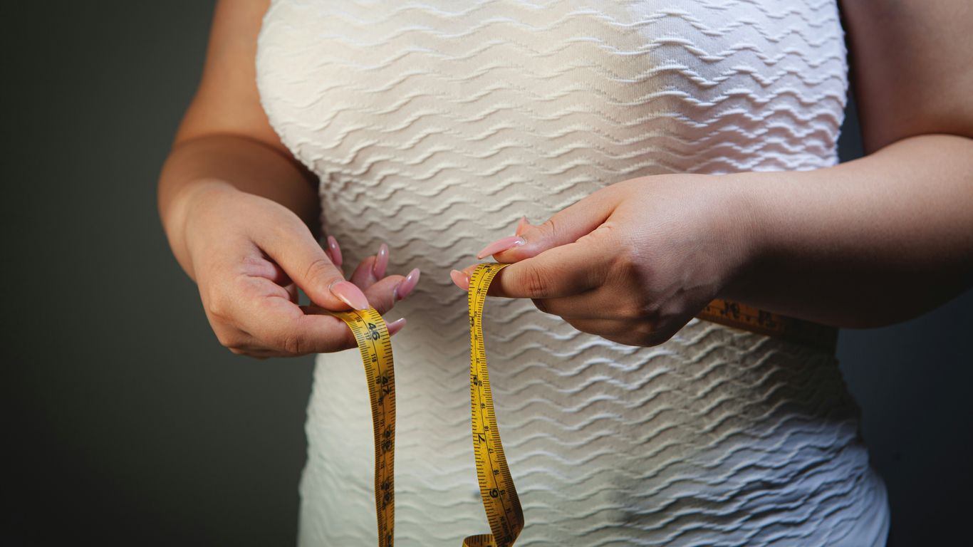 Woman measuring her waist with a tape measure