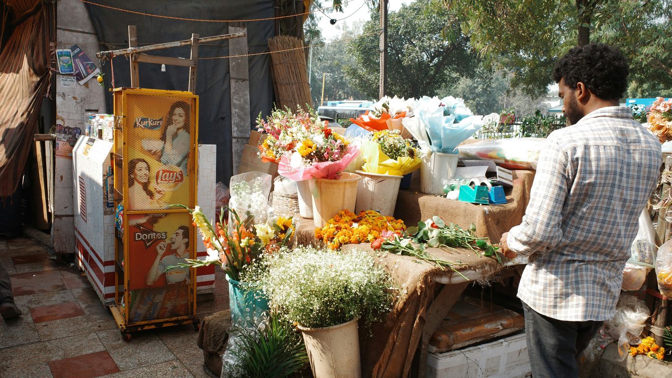 Man stands at a flower stall with bouquets.