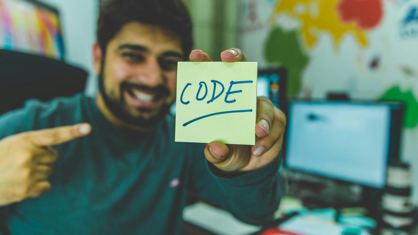 smiling man showing sticky note with code illustration