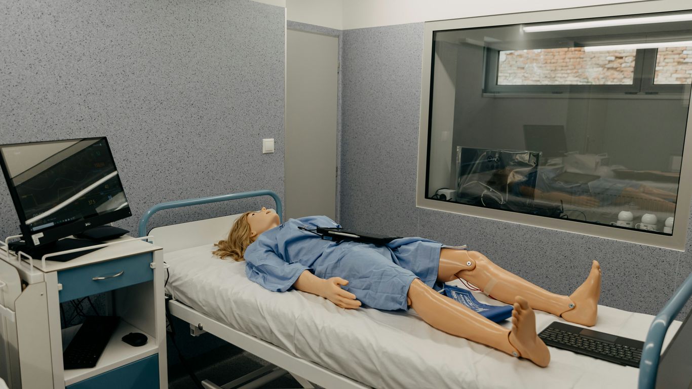 a dummy laying on a hospital bed next to a monitor