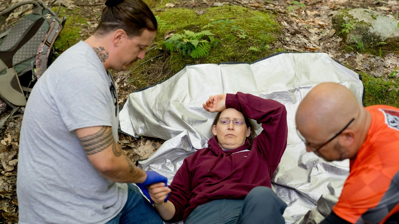 Paramedics attend to an injured person in the woods.