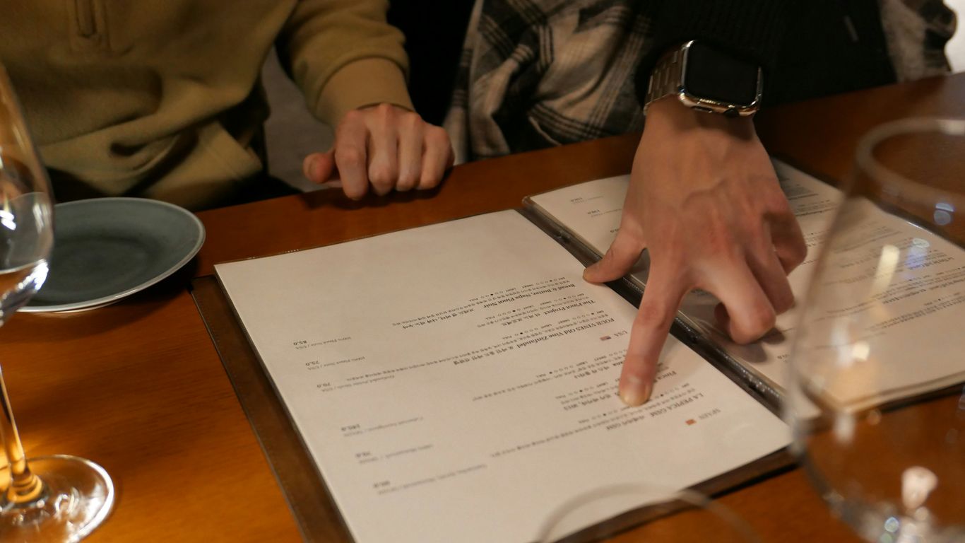 two people sitting at a table with a menu in front of them