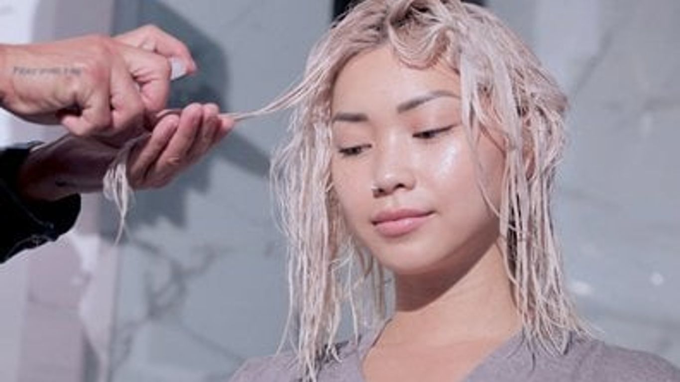 Person getting hair styled with product, salon setting, content expression.