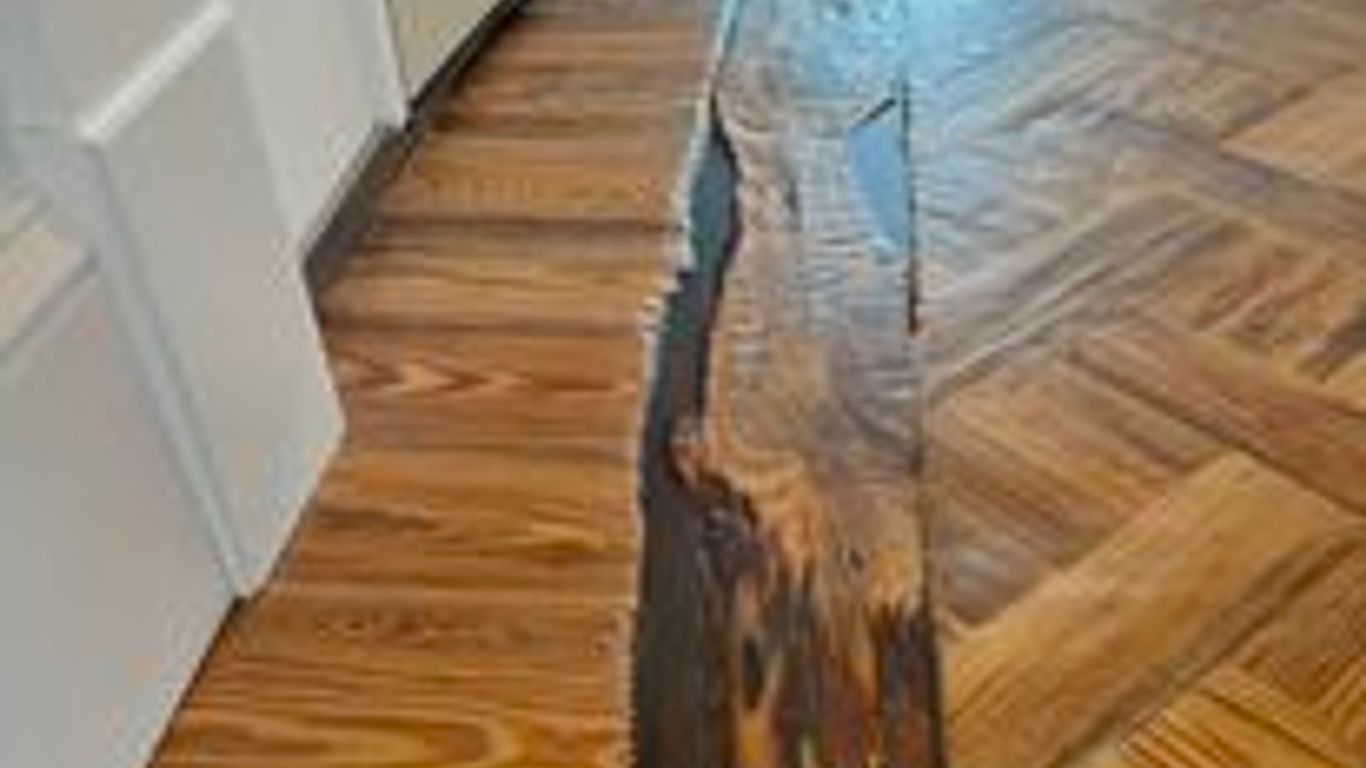 Wood floor with noticeable damage and a crack running through.