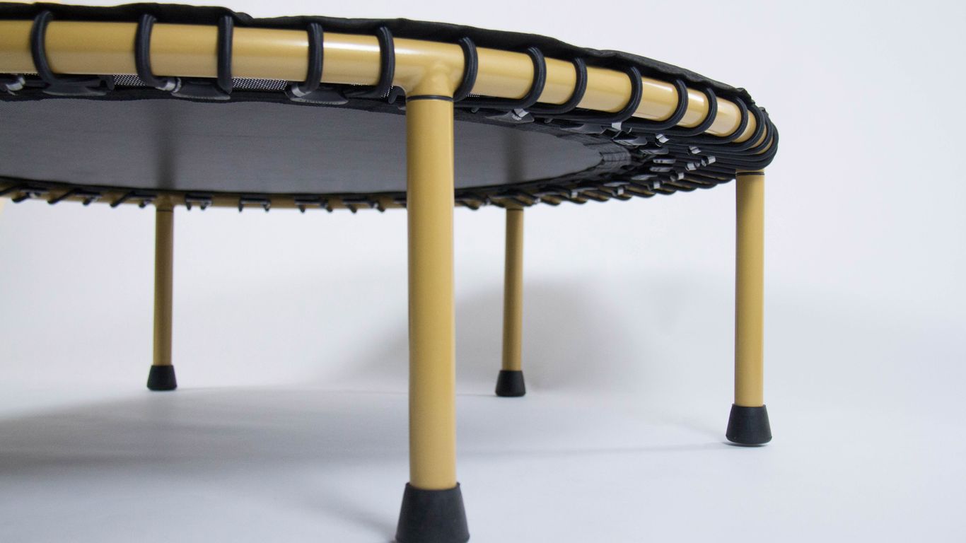 Close-up of a mini trampoline with yellow legs and black mat.