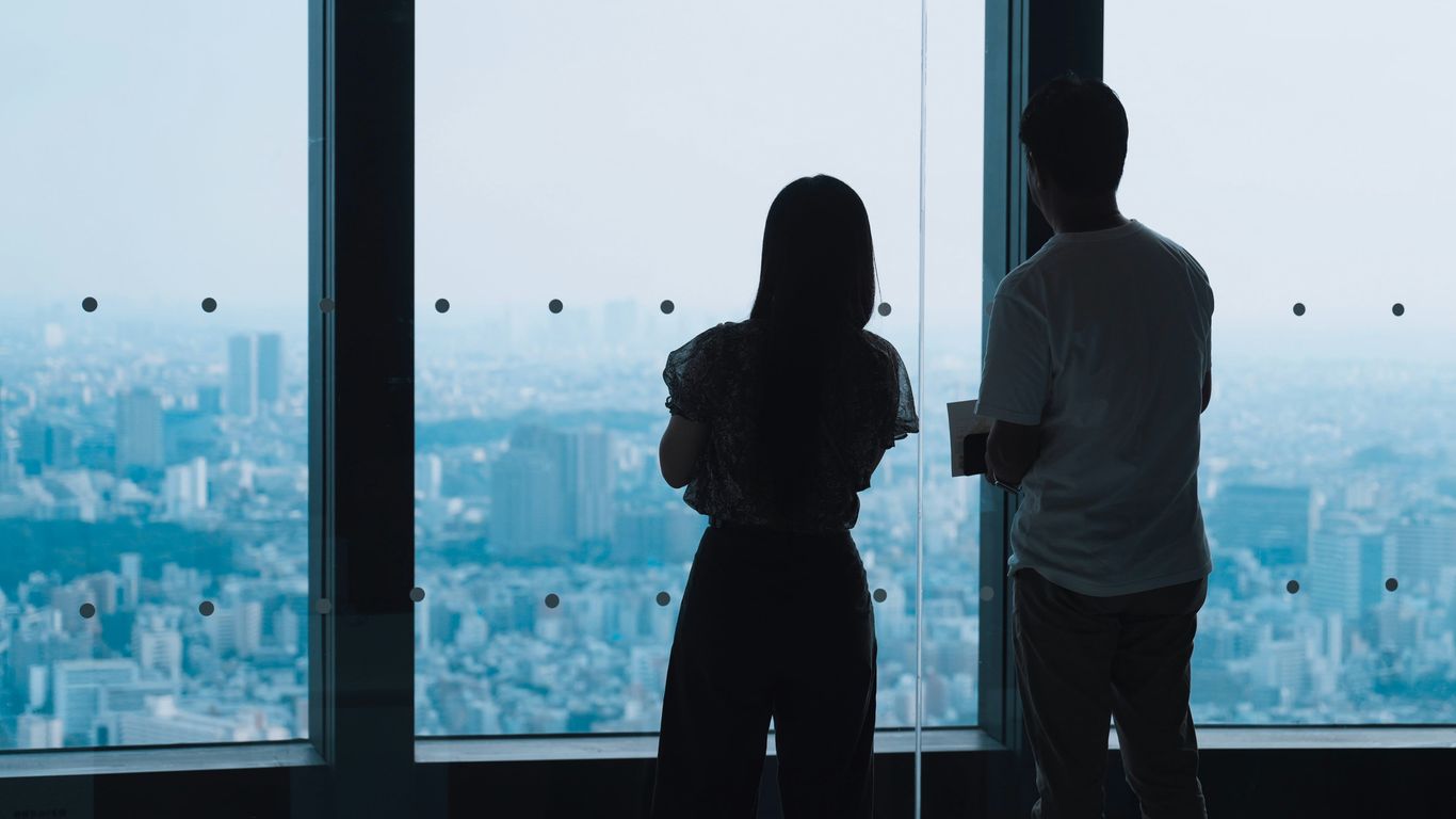 Two people looking out a window at city