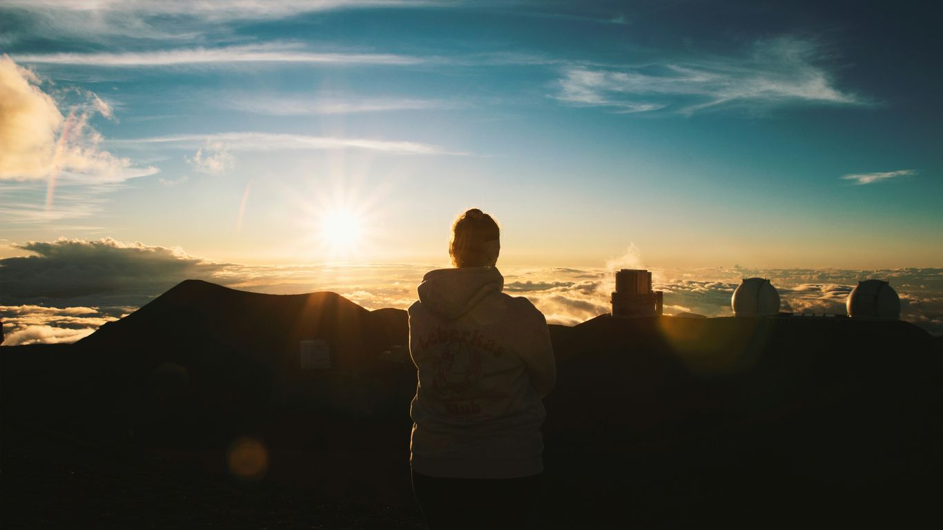 Person watching a sunset over mountains and clouds