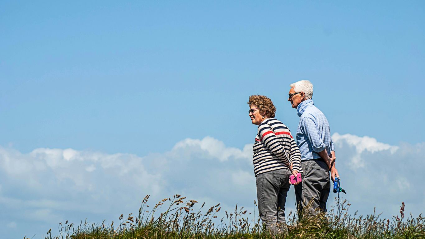 man in white dress shirt and black pants standing beside woman in black and white striped