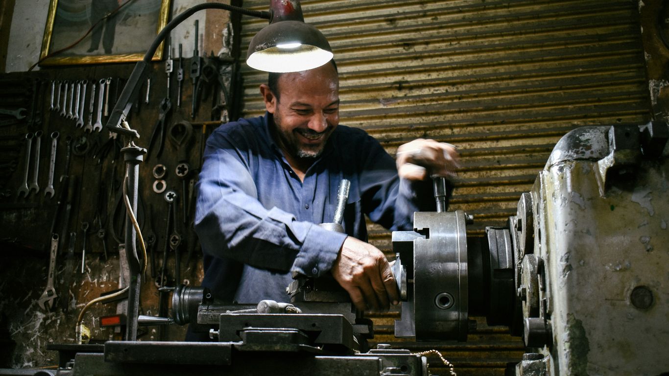 A smiling machinist works in a workshop.