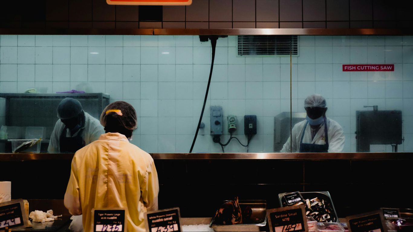 Two chefs working behind a counter in a kitchen.