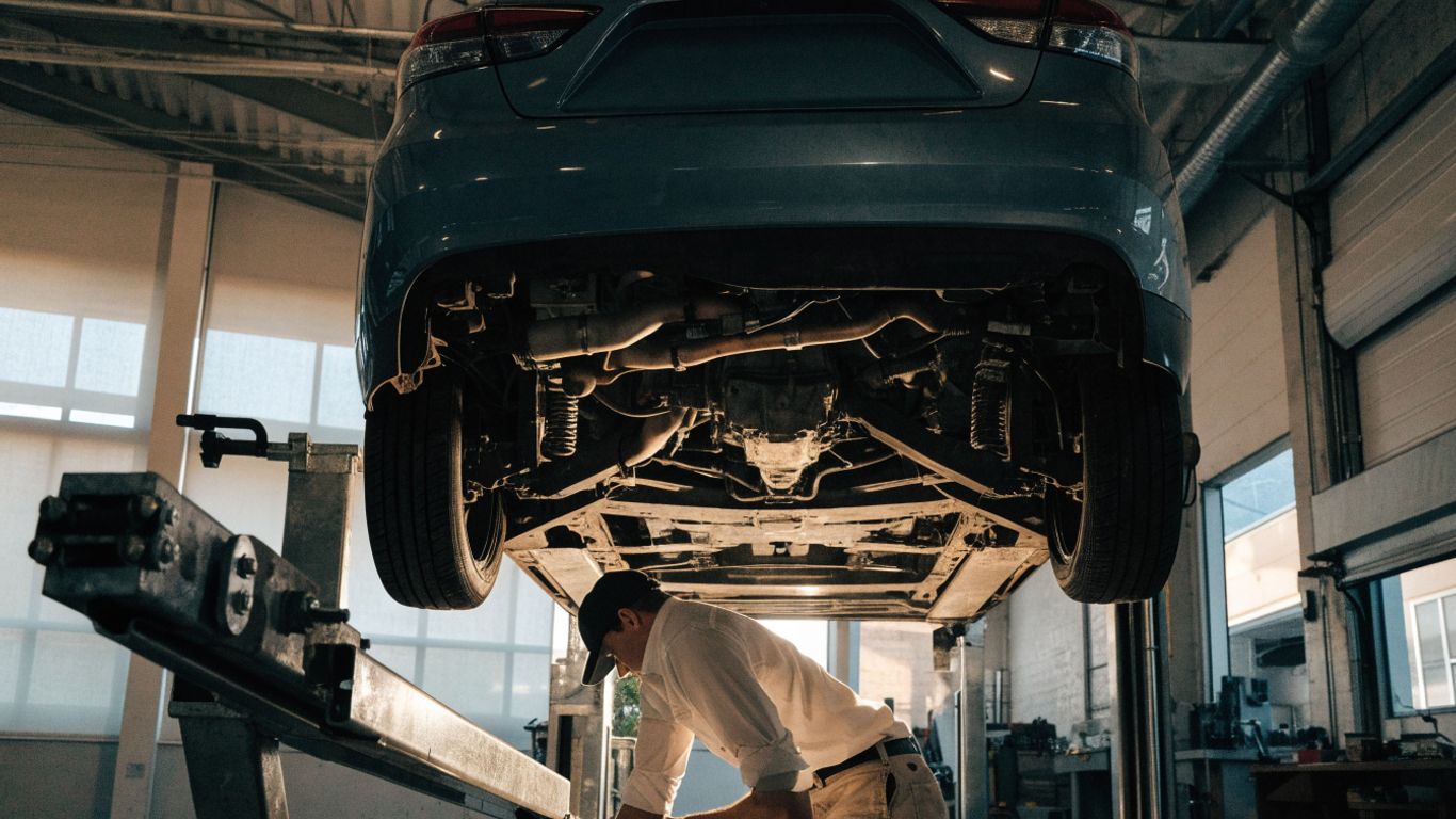 Mechanic checking a transmission beneath a raised car