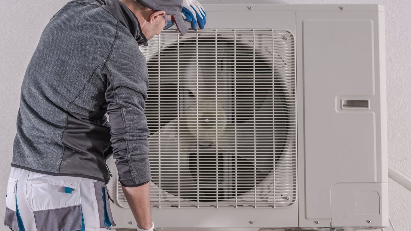 Technician inspecting the outdoor unit of an air conditioning system.
