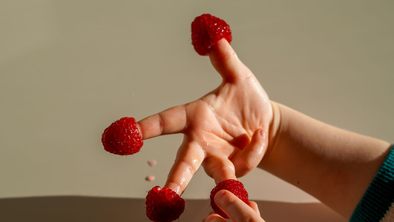 a person holding raspberries in their hands