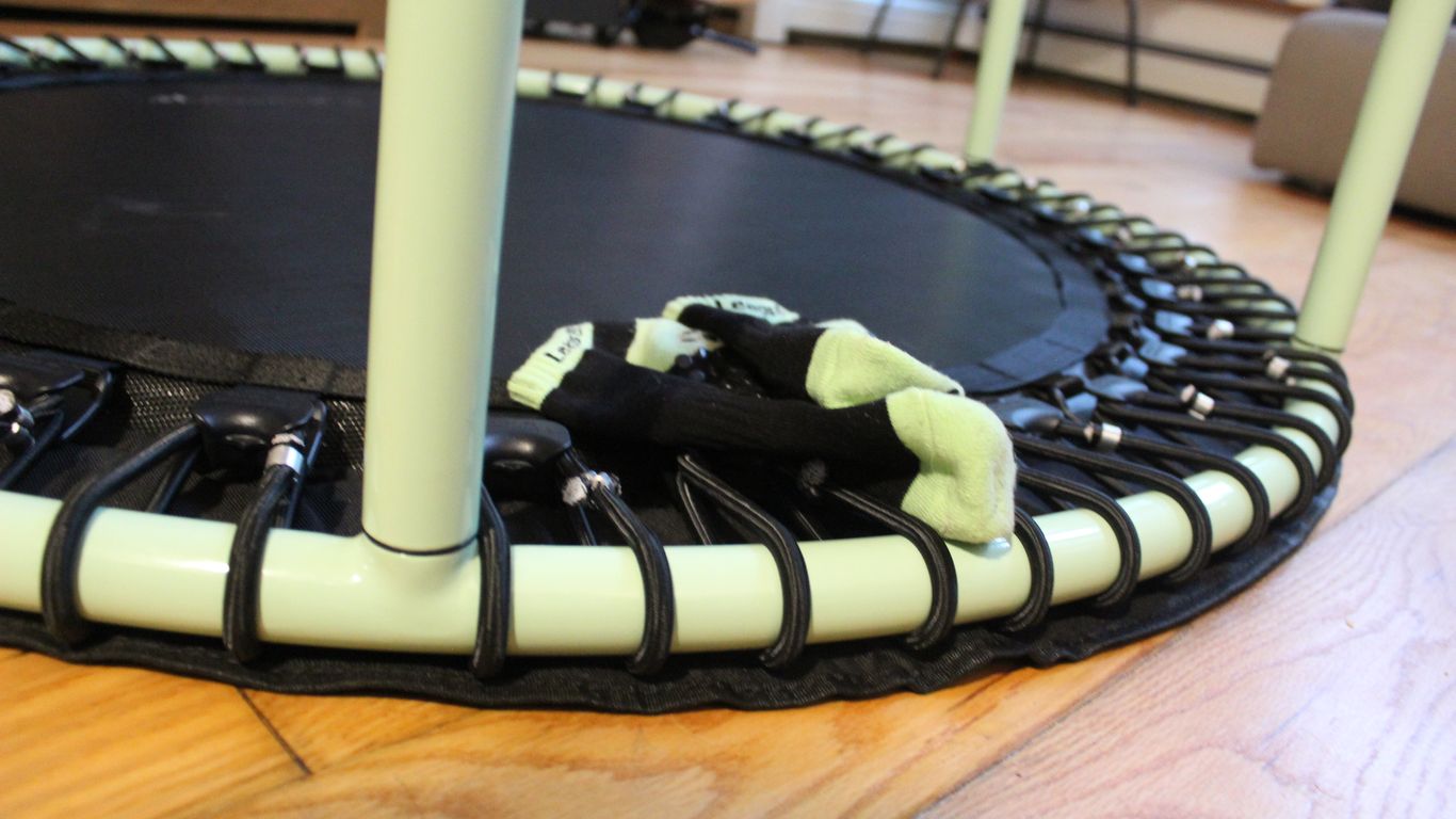 Small trampoline with green frame and socks on top.