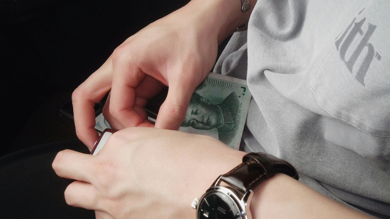 A person holding a watch and a money in their hand