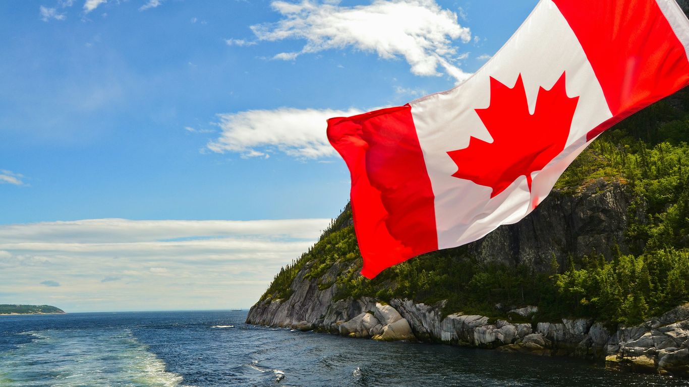 red and white flag on rock formation near body of water during daytime