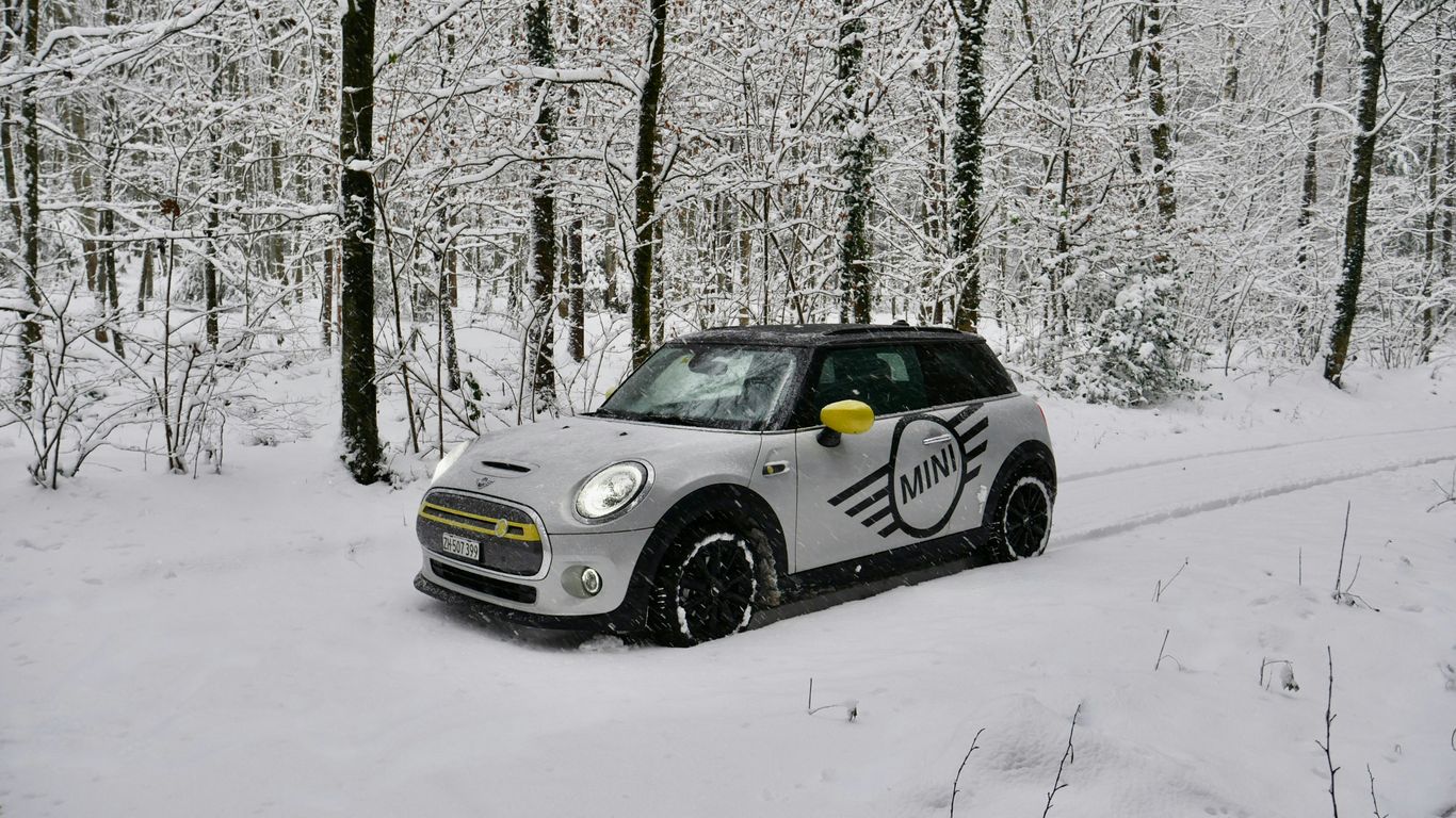 a small car driving through a snow covered forest