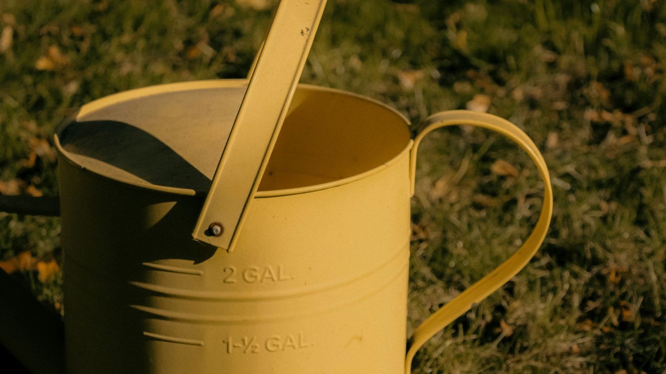 a yellow watering can with a spoon sticking out of it