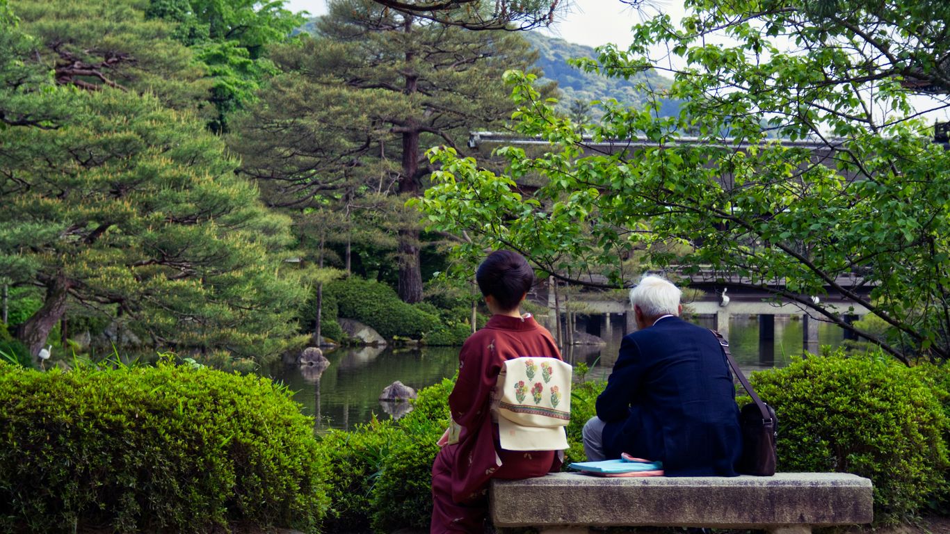 two people sitting on a bench in a park