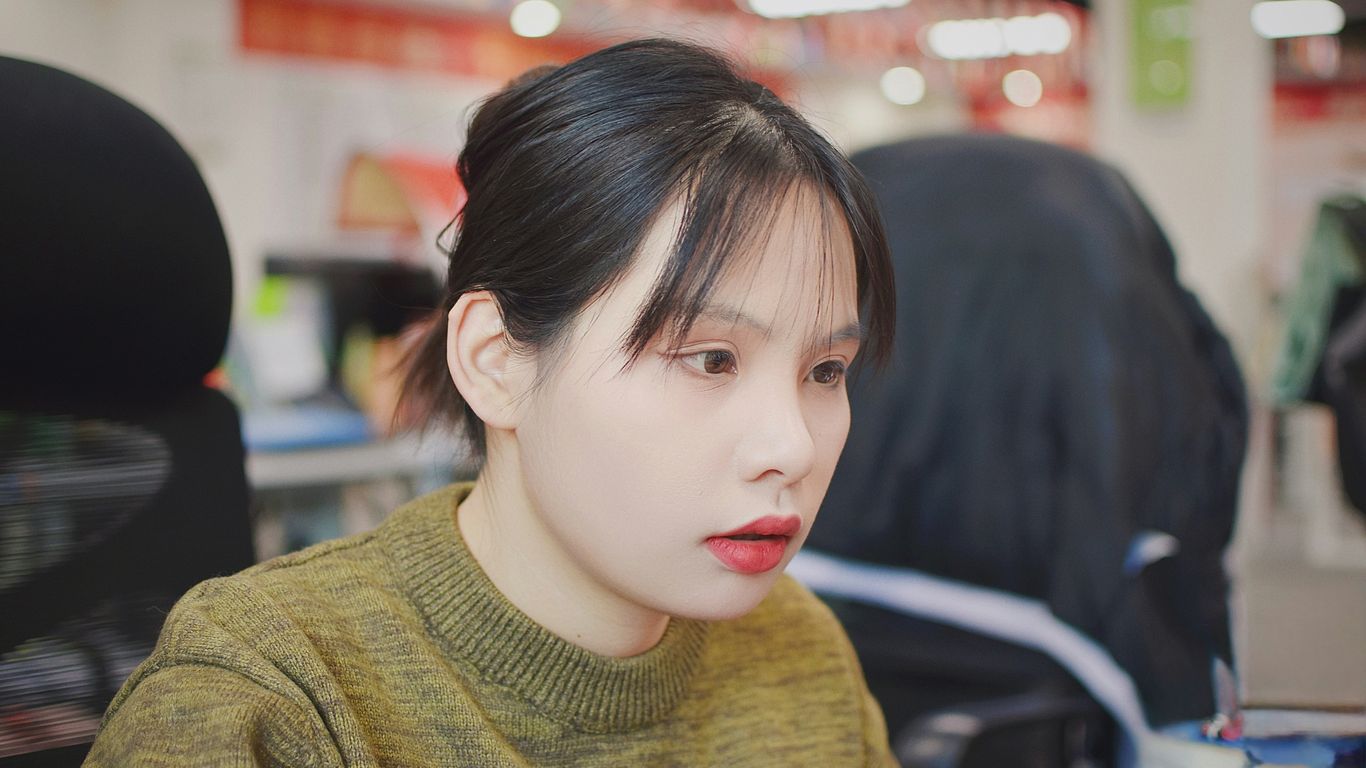 A woman sitting at a desk with a cell phone in her hand