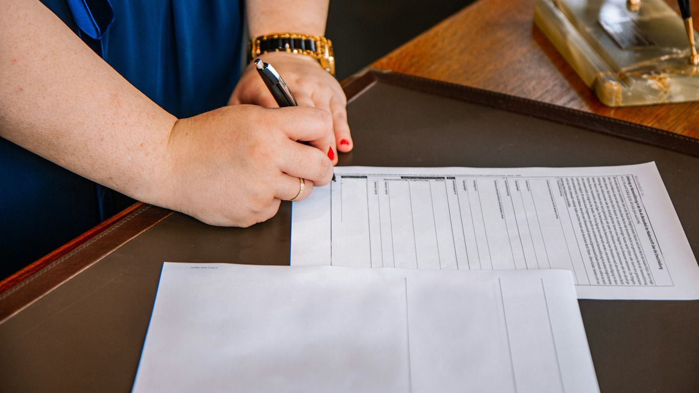 person holding pen and writing on paper
