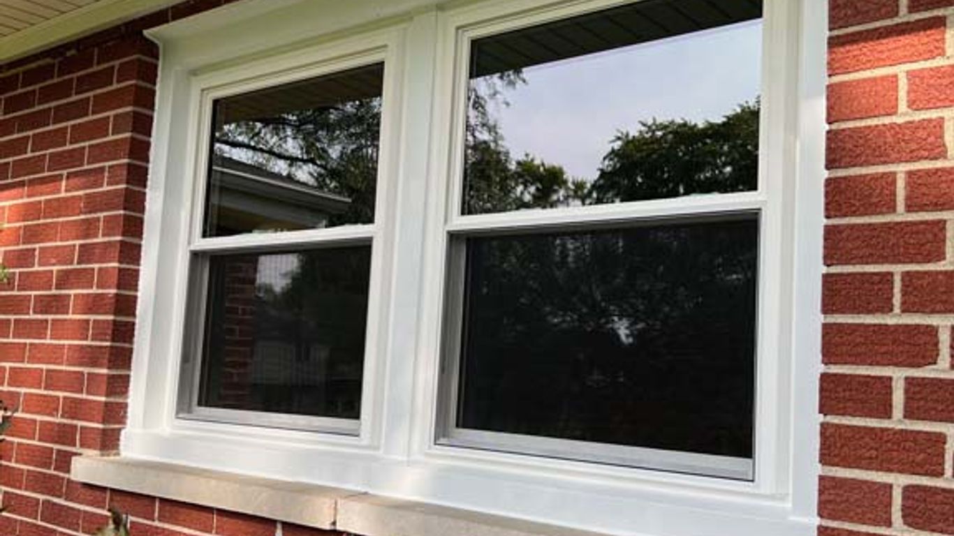 A newly installed white double-pane window on a brick house.