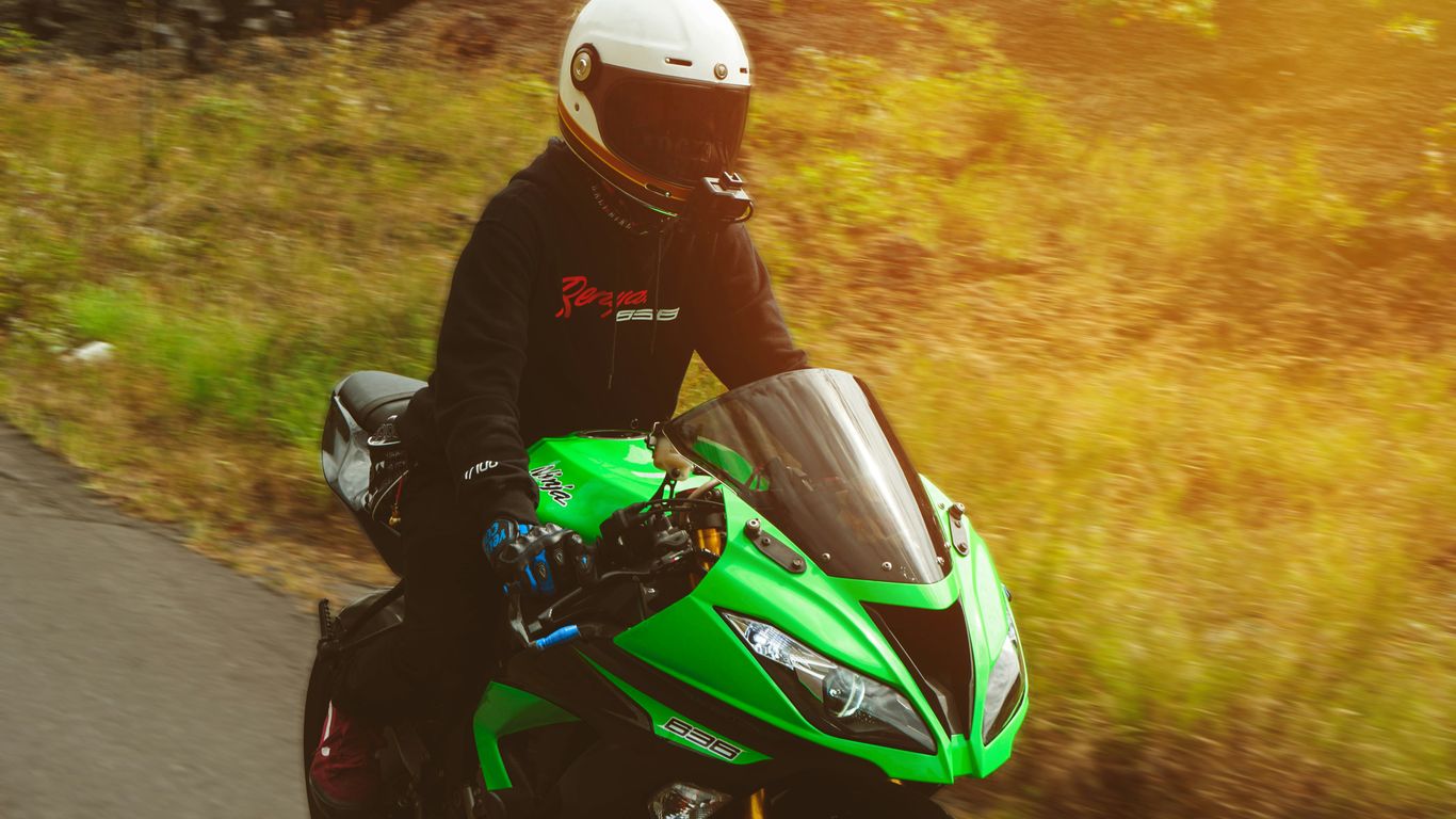 a person riding a green motorcycle on a road