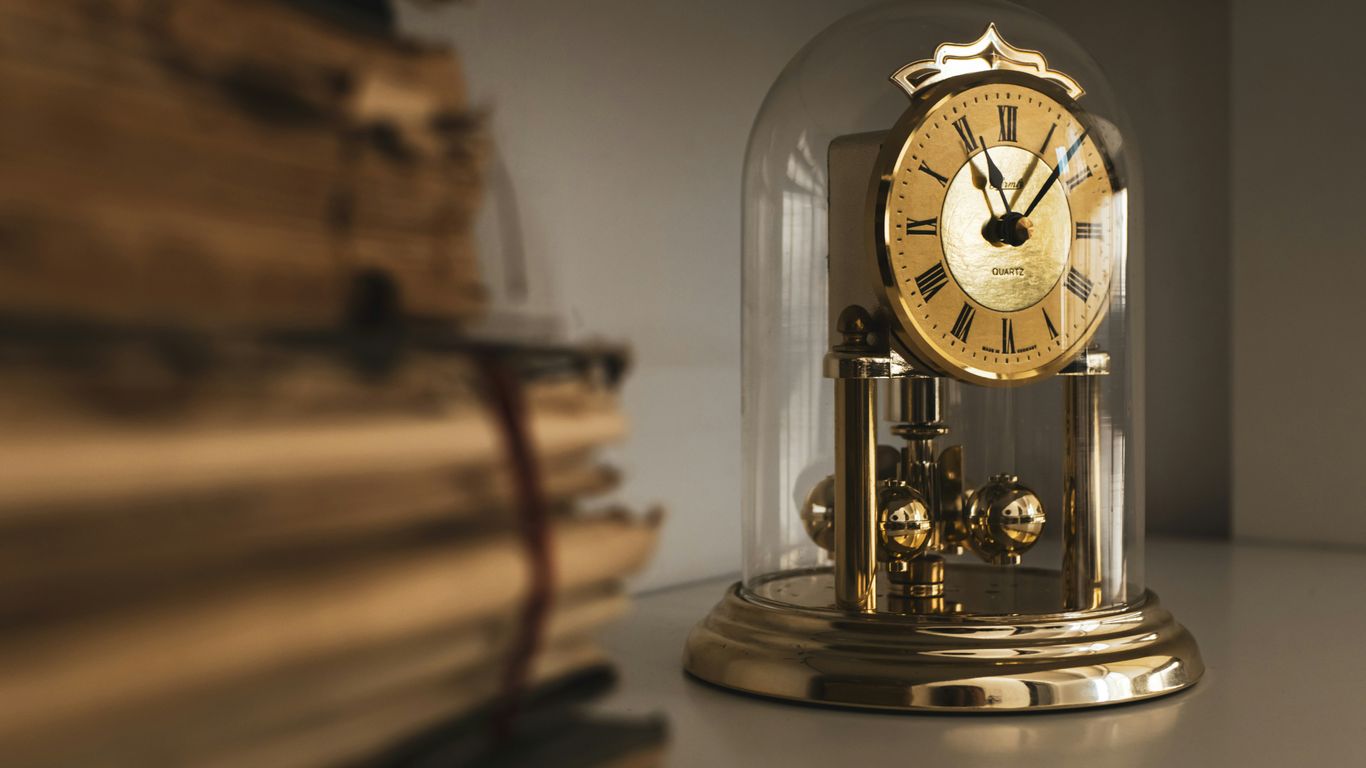 a clock sitting on top of a table next to a stack of books