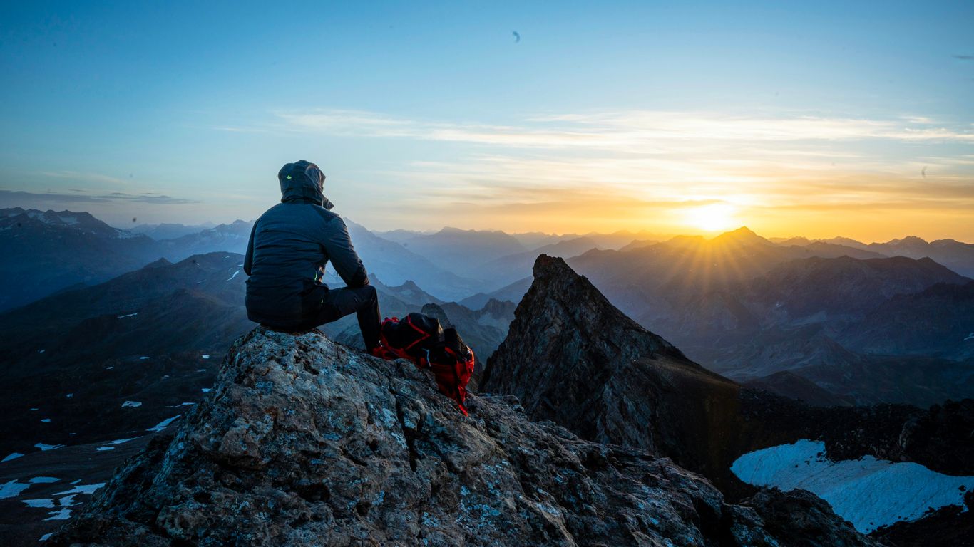 man in black jacket sitting on rock during daytime