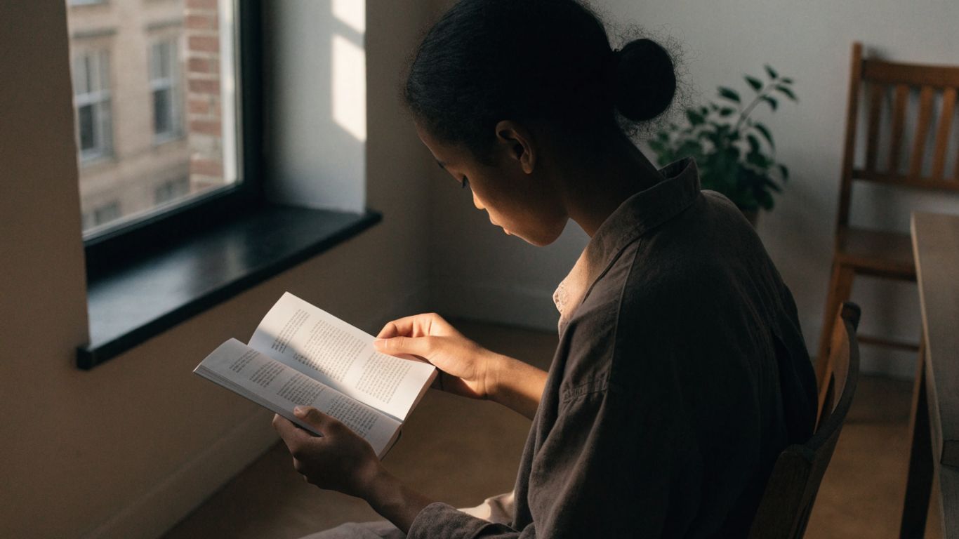 Reader exploring a poetry book beside a quiet window