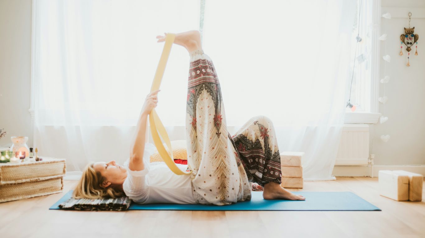 Person practicing a strap stretch on a yoga mat