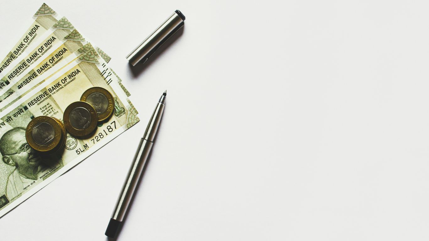 gray pen beside coins on Indian rupee banknotes