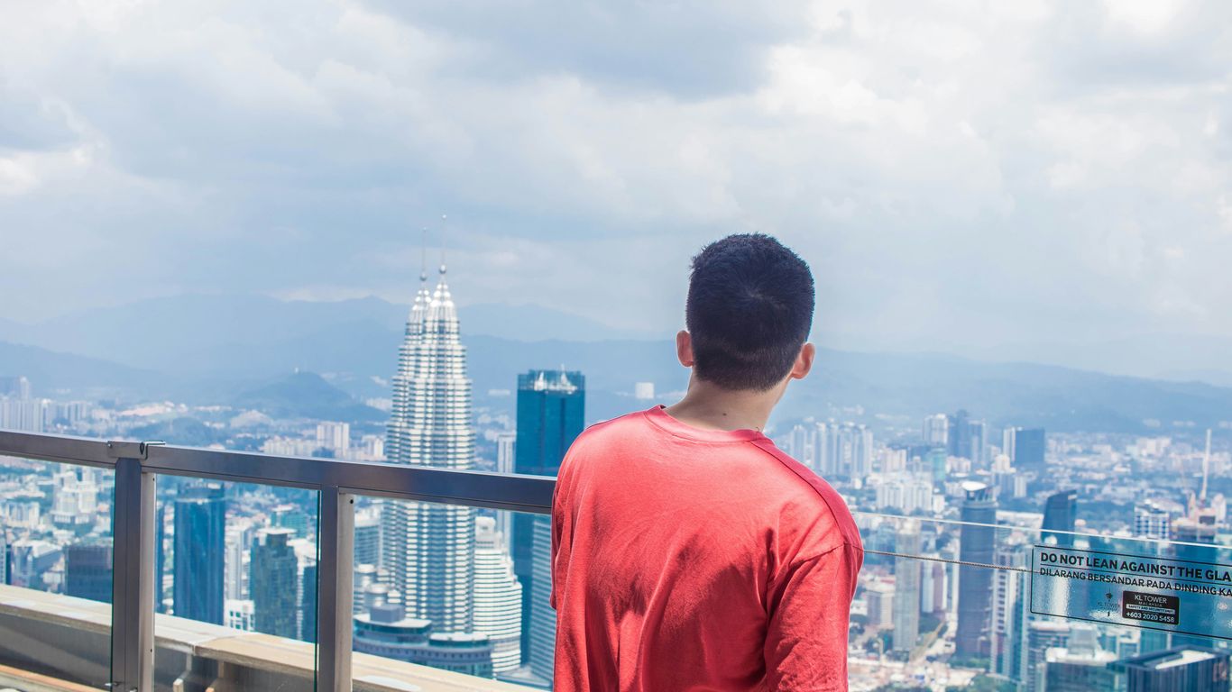 man in red crew neck t-shirt standing on building during daytime