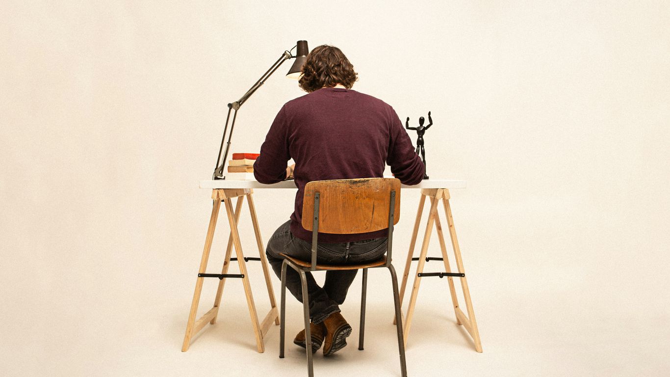 man in brown shirt sitting on brown wooden chair