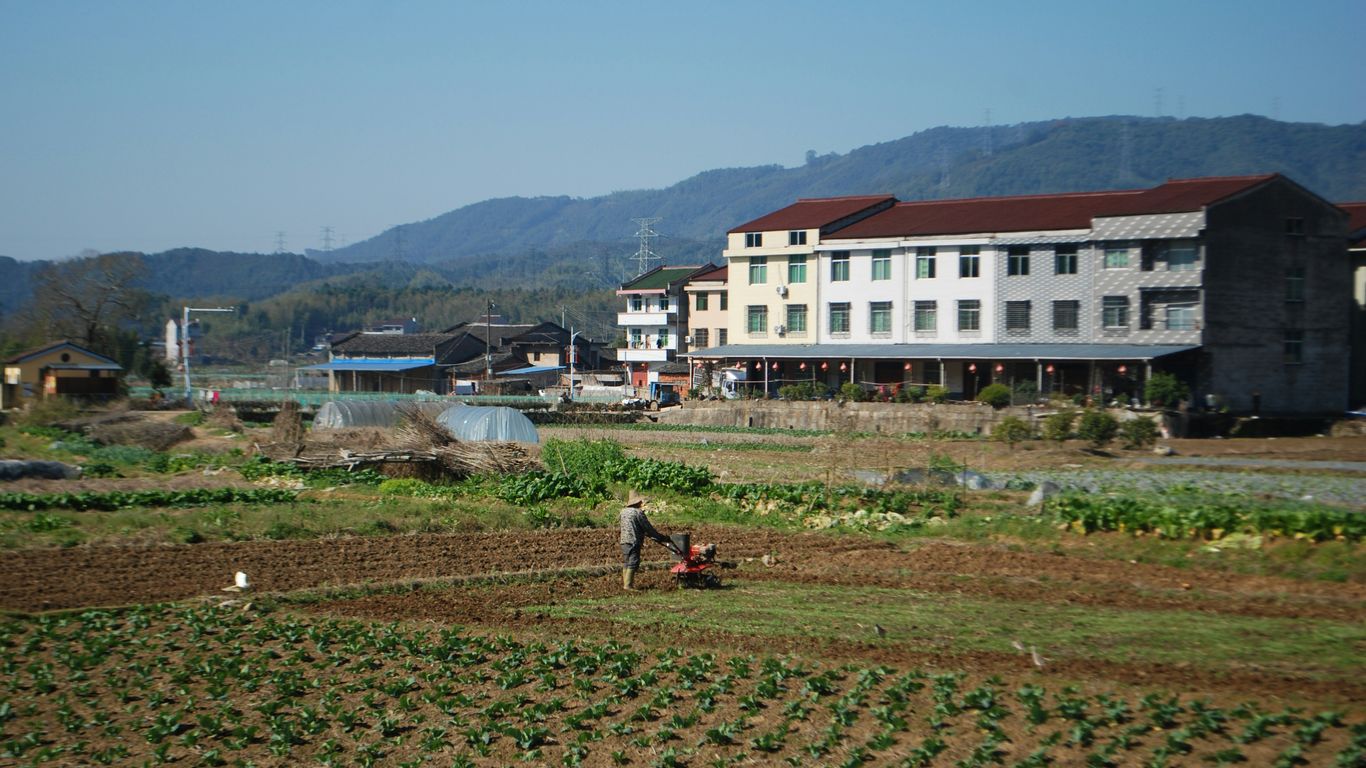 a man is plowing a field in front of a building