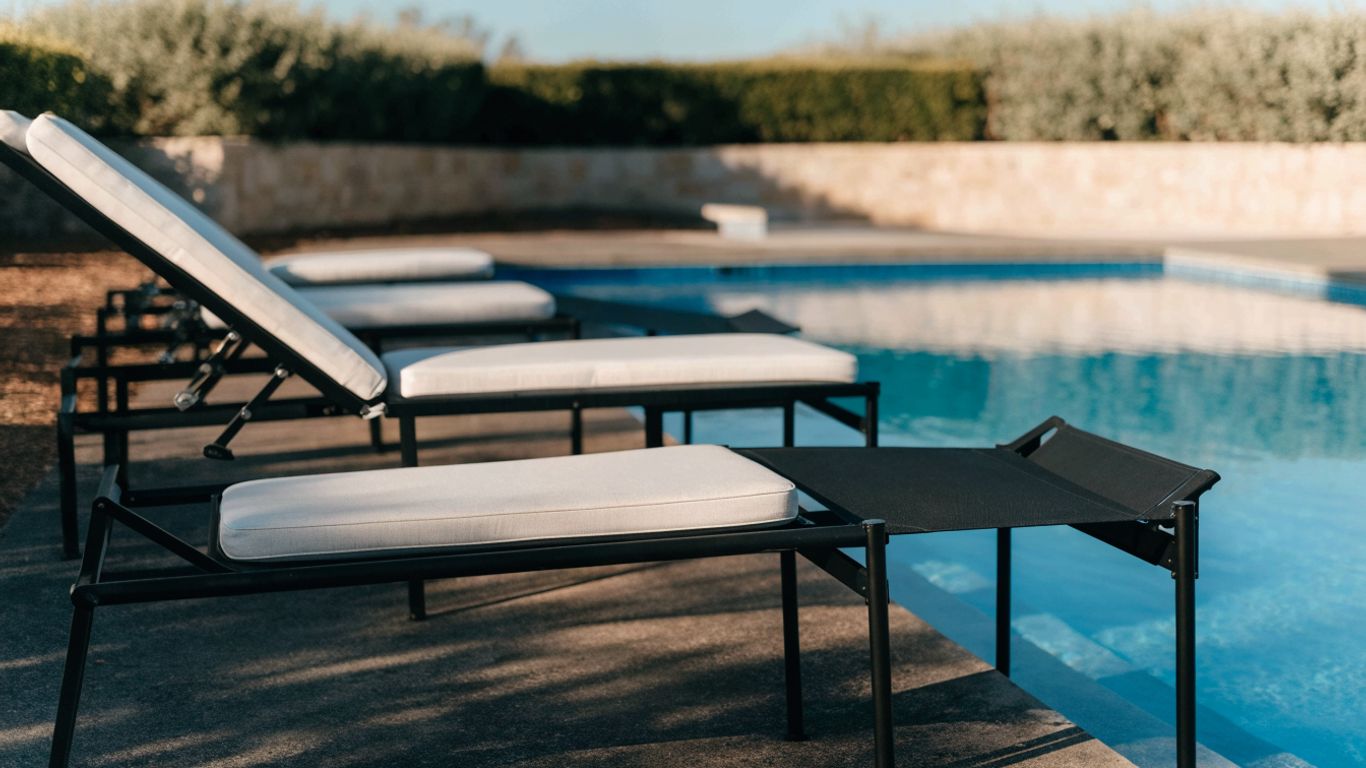 Reclining loungers arranged beside a blue pool