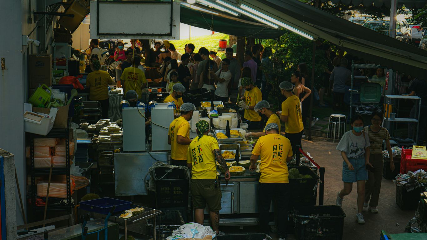 People gathered at an outdoor food stall with vendors cooking