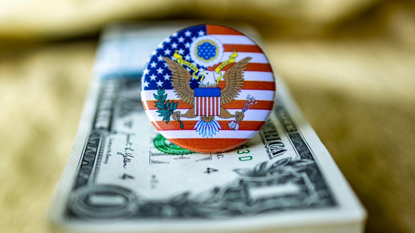 An american flag pin sitting on top of a one dollar bill