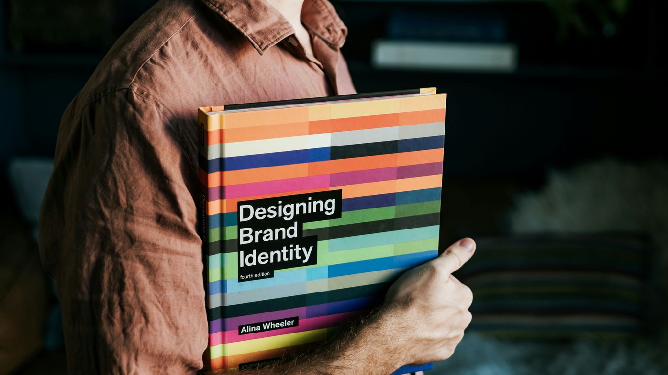 a man holding a book that says designing brand identity