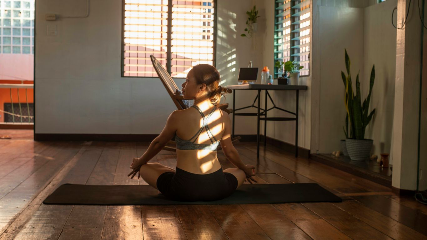 woman in white tank top and black shorts sitting on brown wooden floor