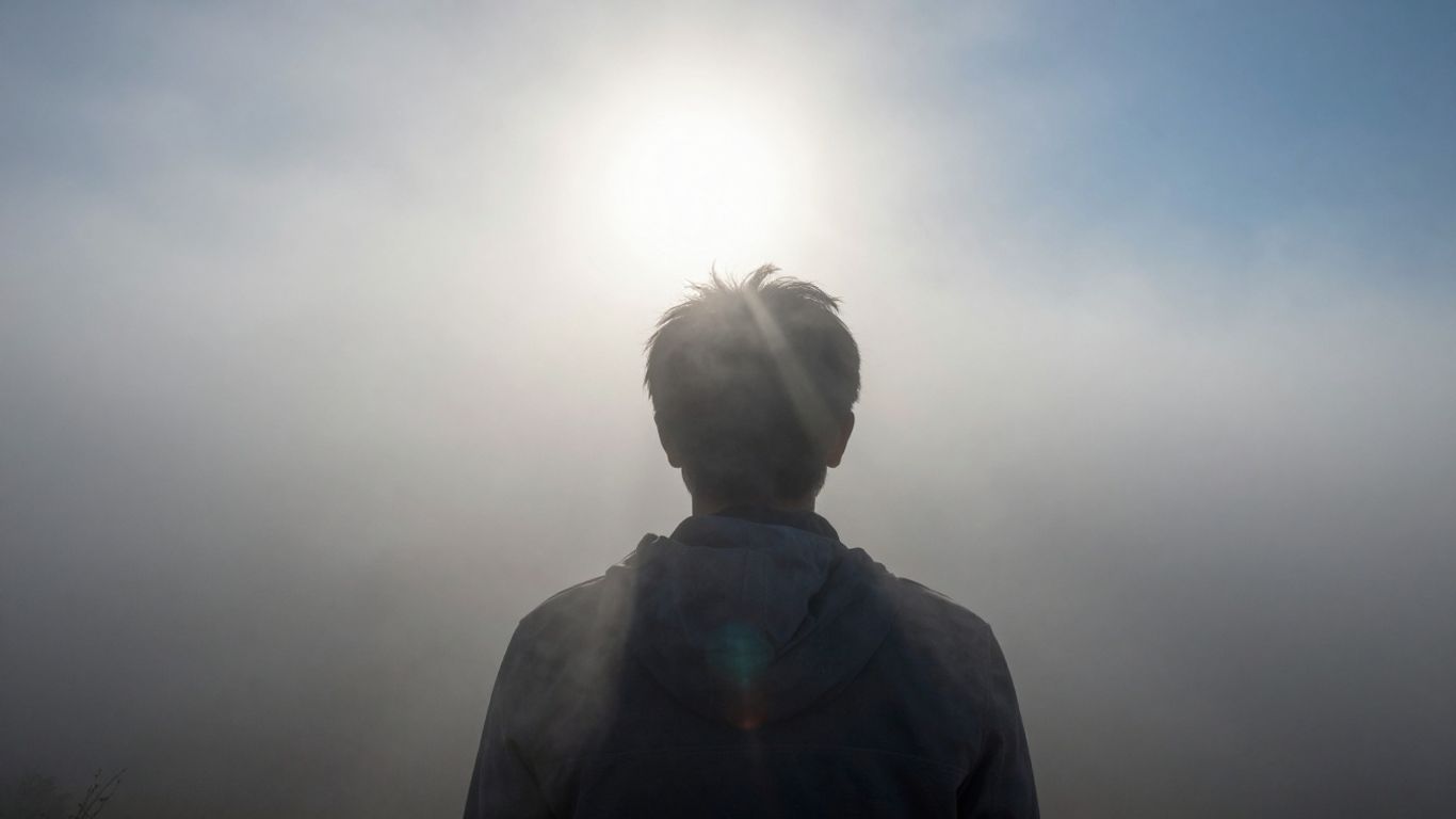 Person's head emerging from fog into clear light.