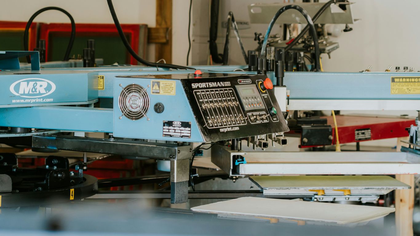 Industrial screen printing machine in a workshop setting.
