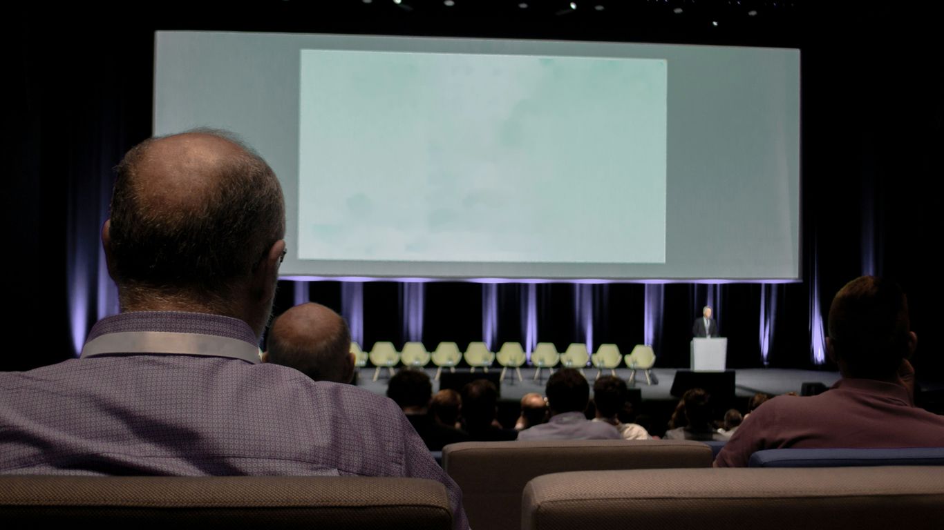 a group of people sitting in front of a projection screen